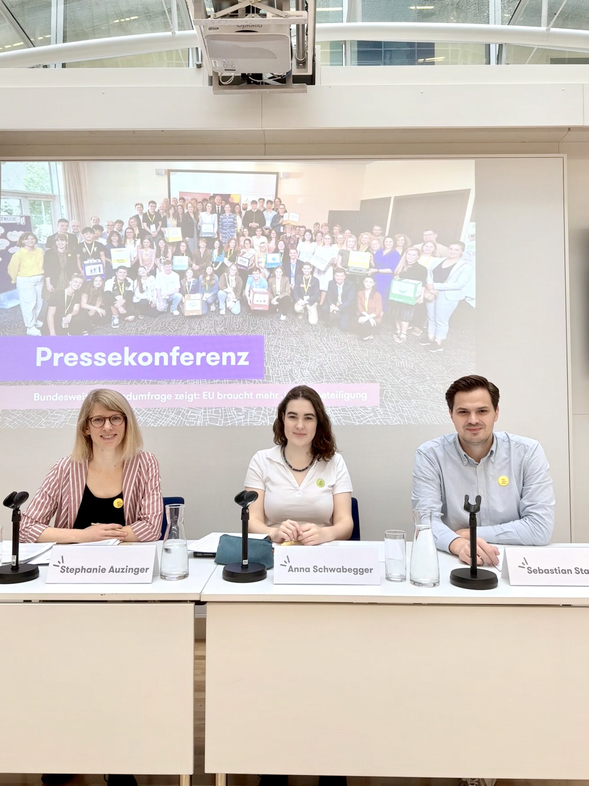 Das Bild zeigt drei Personen auf dem Podium einer Pressekonferenz zu den Ergebnisse der Umfrage 